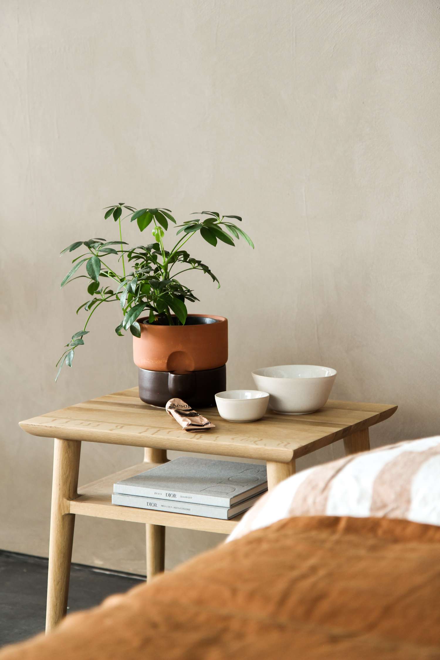 quarto bege com uma mesa lateral de madeira e lençóis de terra