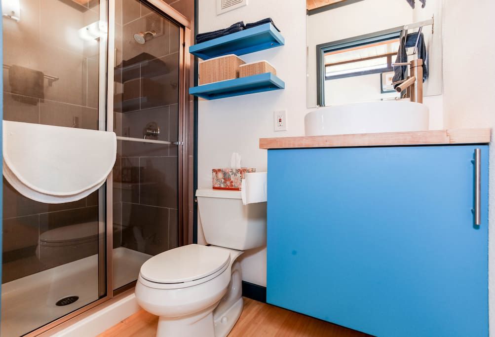 banheiro minúsculo com portas de vidro para o chuveiro e penteadeira azul