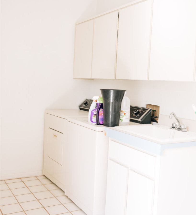 All white, outdated laundry room with lots of storage.