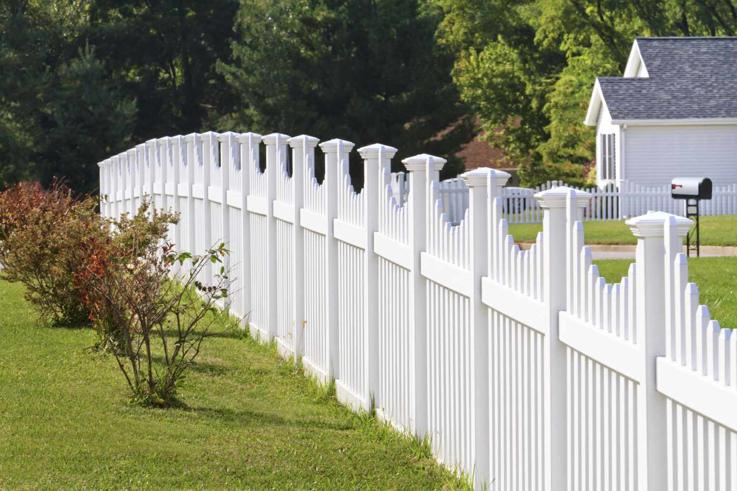 Ornate white vinyl fence running across a yard