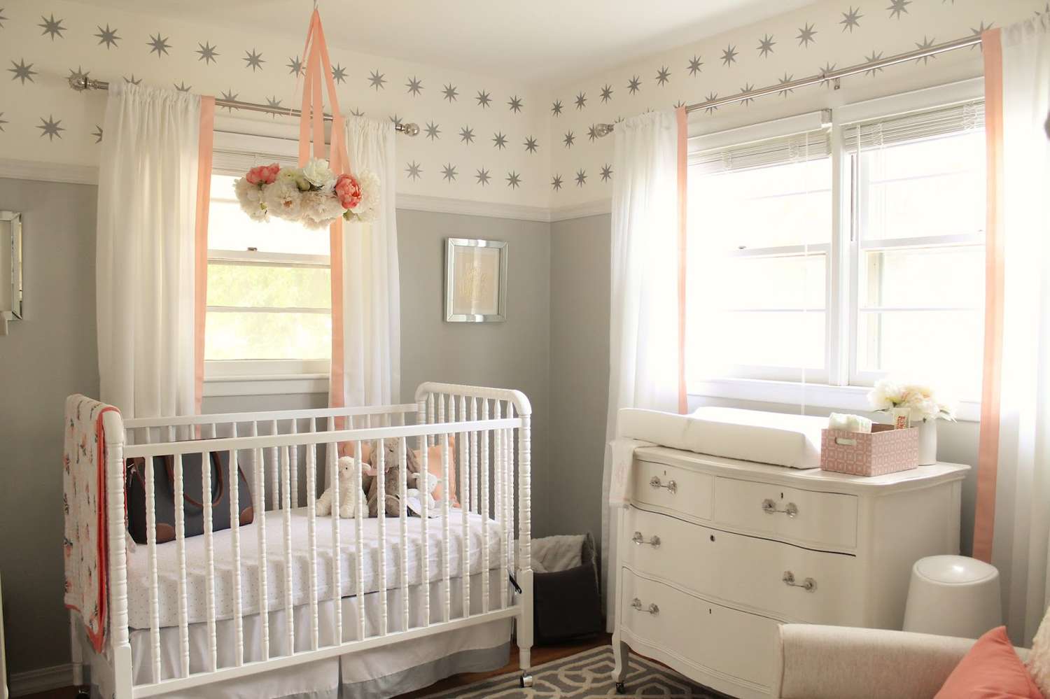 Espaço de quarto de bebê cinza, branco e rosa com toques de cor