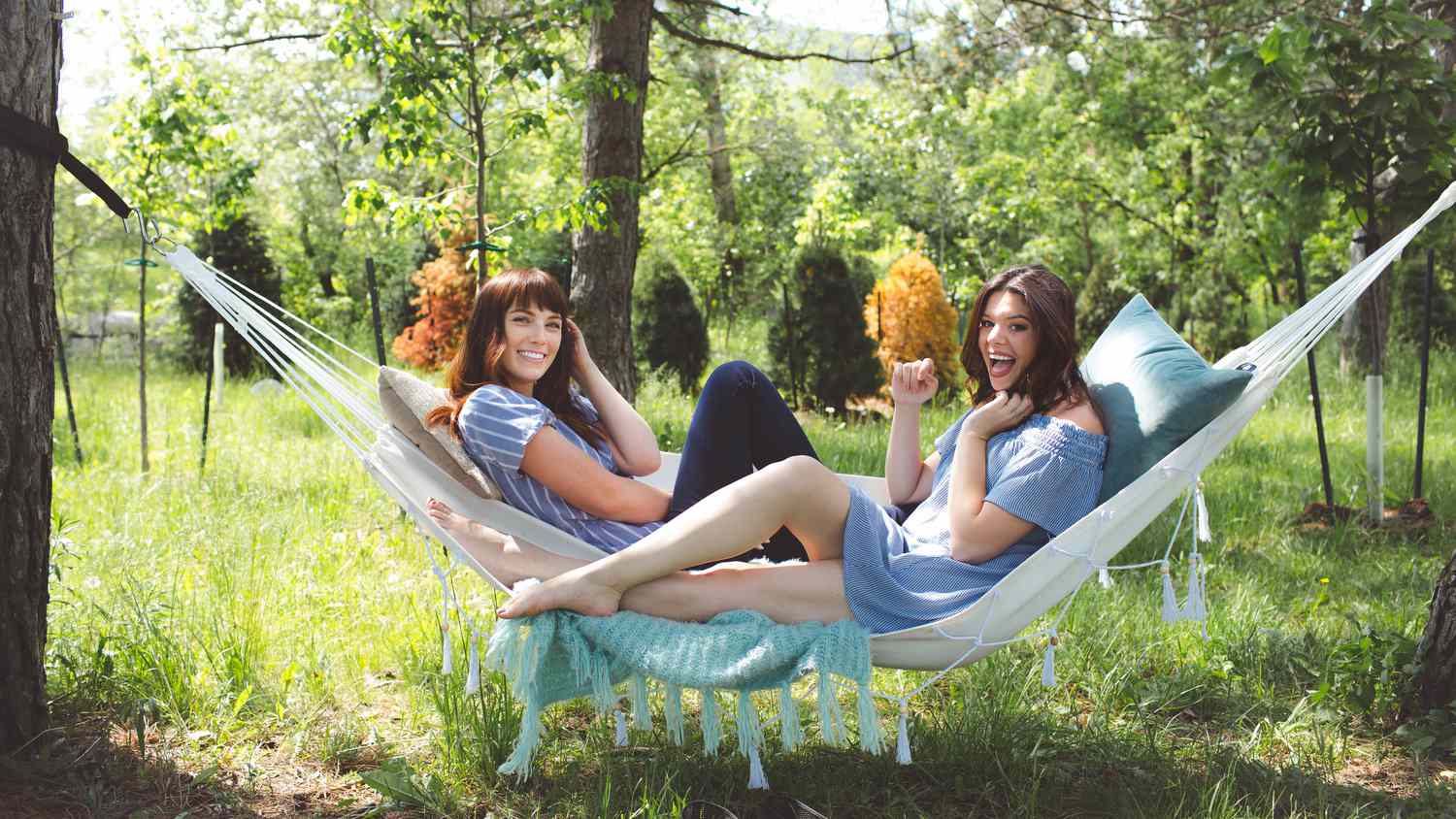 Duas garotas relaxando em redes brancas na floresta.