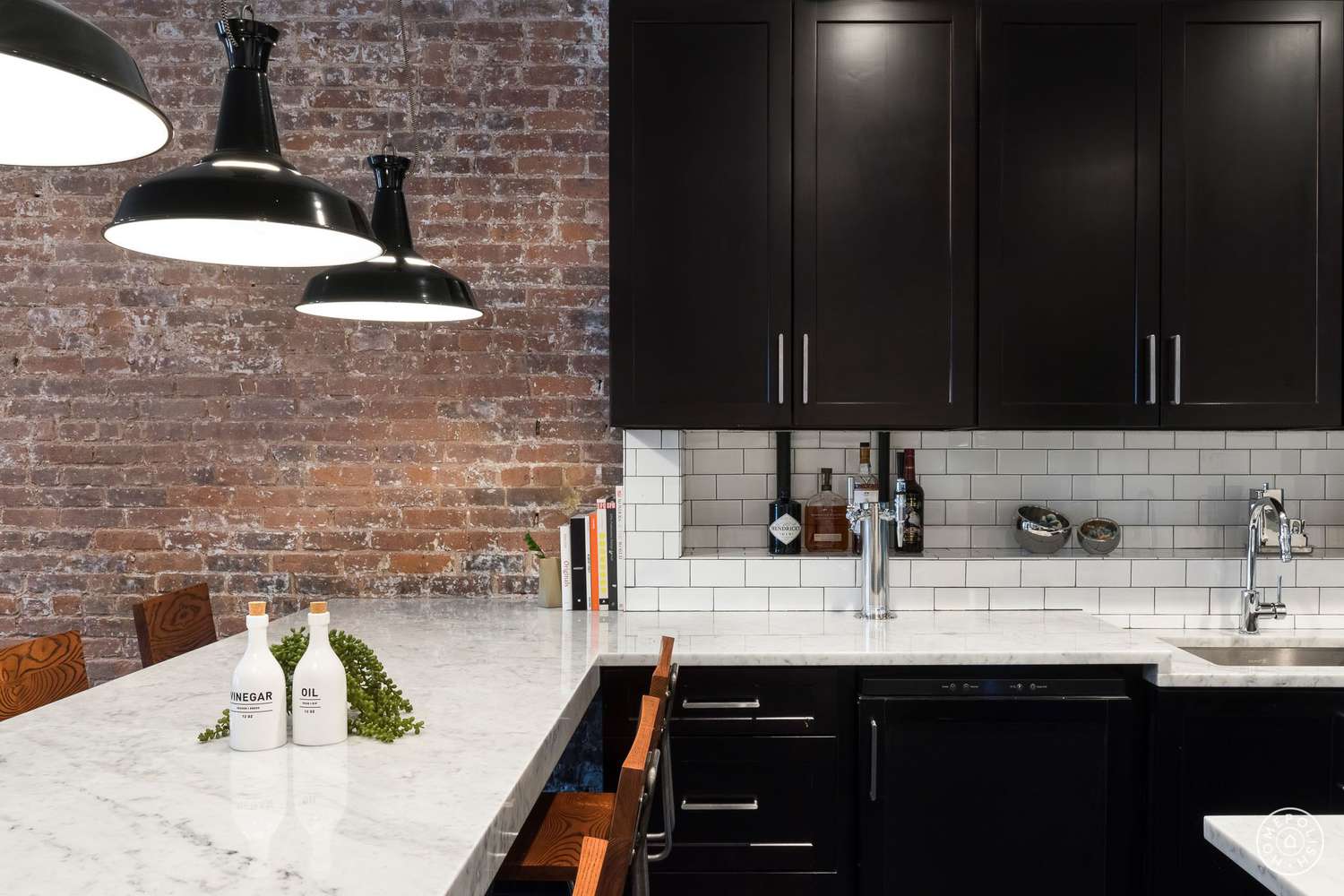 Schwarze Küche mit Backsteinwand und schwarzen Pendelleuchten
