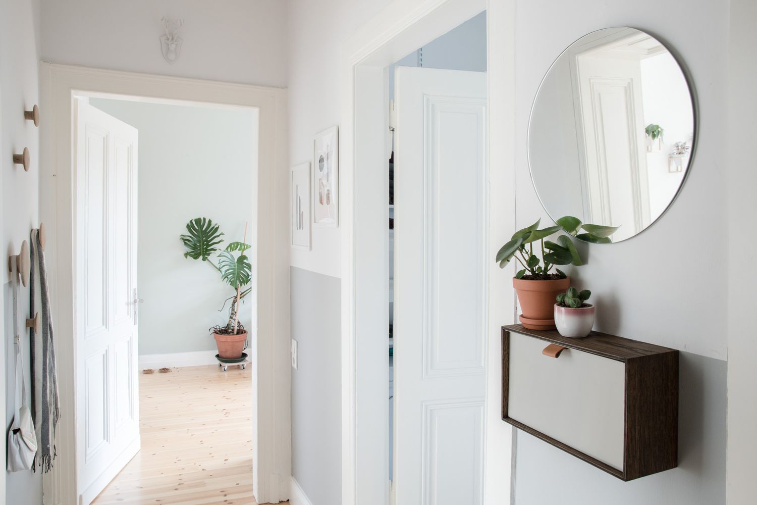 Entrada minimalista com espelho redondo, plantas e armazenamento montado na parede