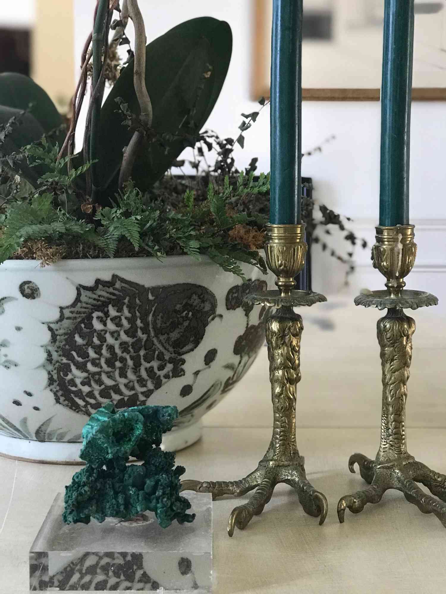Antiguos candelabros con tallos de pata de pájaro se exhiben cerca de una maceta en casa de la interiorista Victoria Pouncey