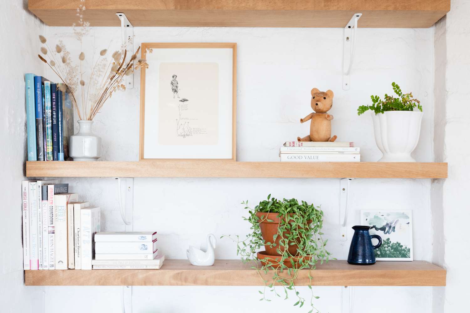 Prateleiras abertas de madeira decoradas com livros, plantas domésticas e pequenos itens de decoração