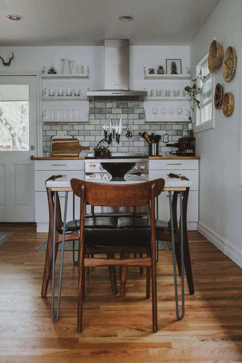 cozinha com backsplash de azulejos brancos e mesa de cozinha rústica