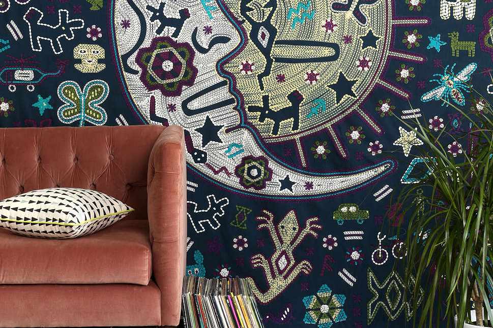 Wandteppich mit einem Mond neben einer malvenfarbenen Couch