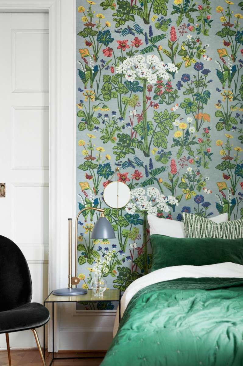 Schlafzimmer mit bunter Blumentapete und grünen Akzenten