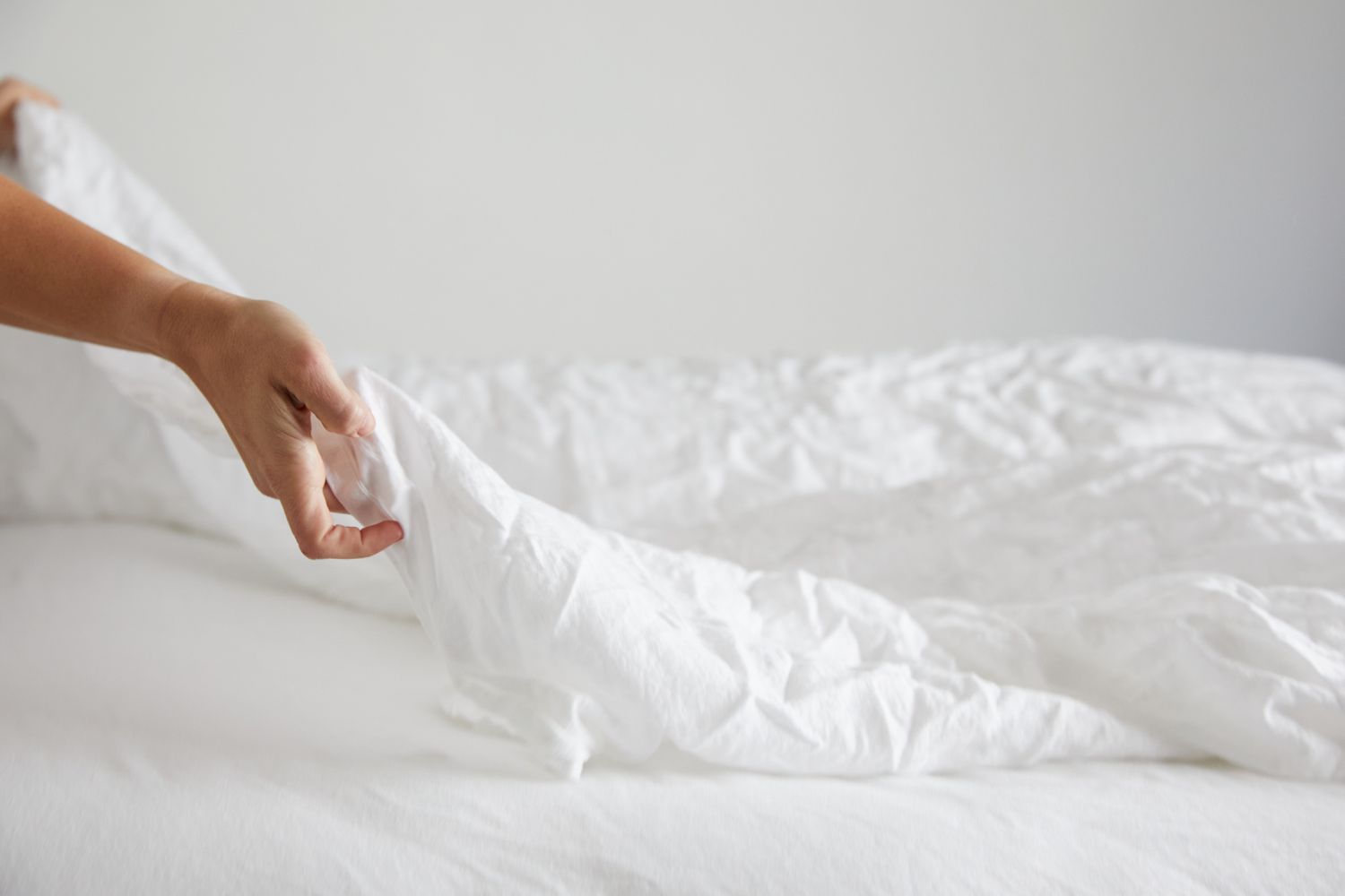 person putting sheets on a bed