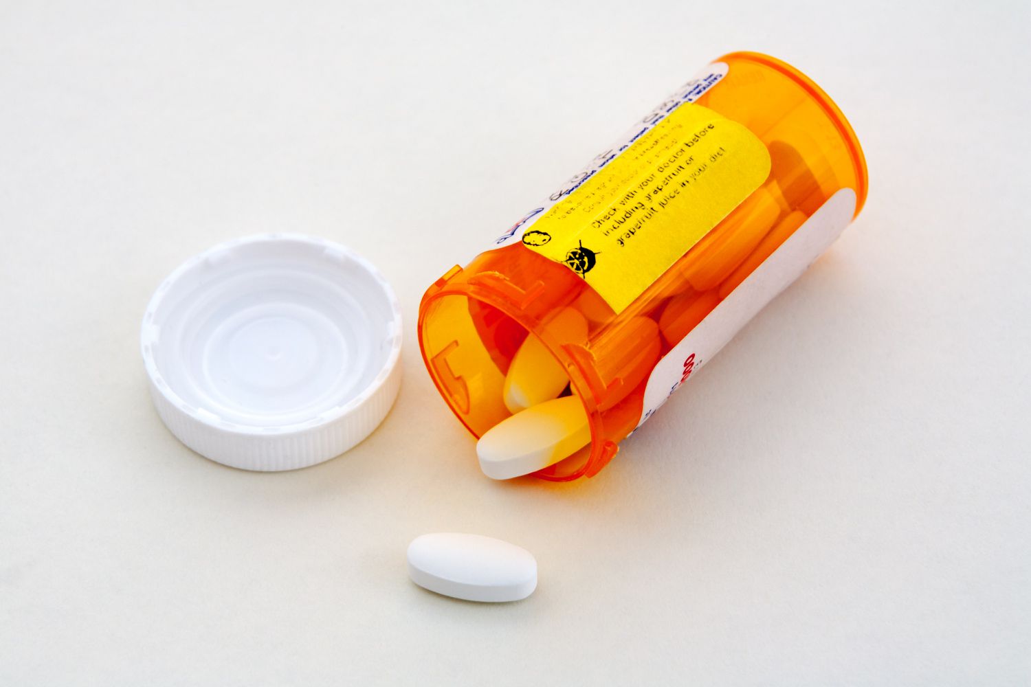 Verschreibungspflichtige Medikamentenflasche offen mit weißen Pillen, die herausquellen