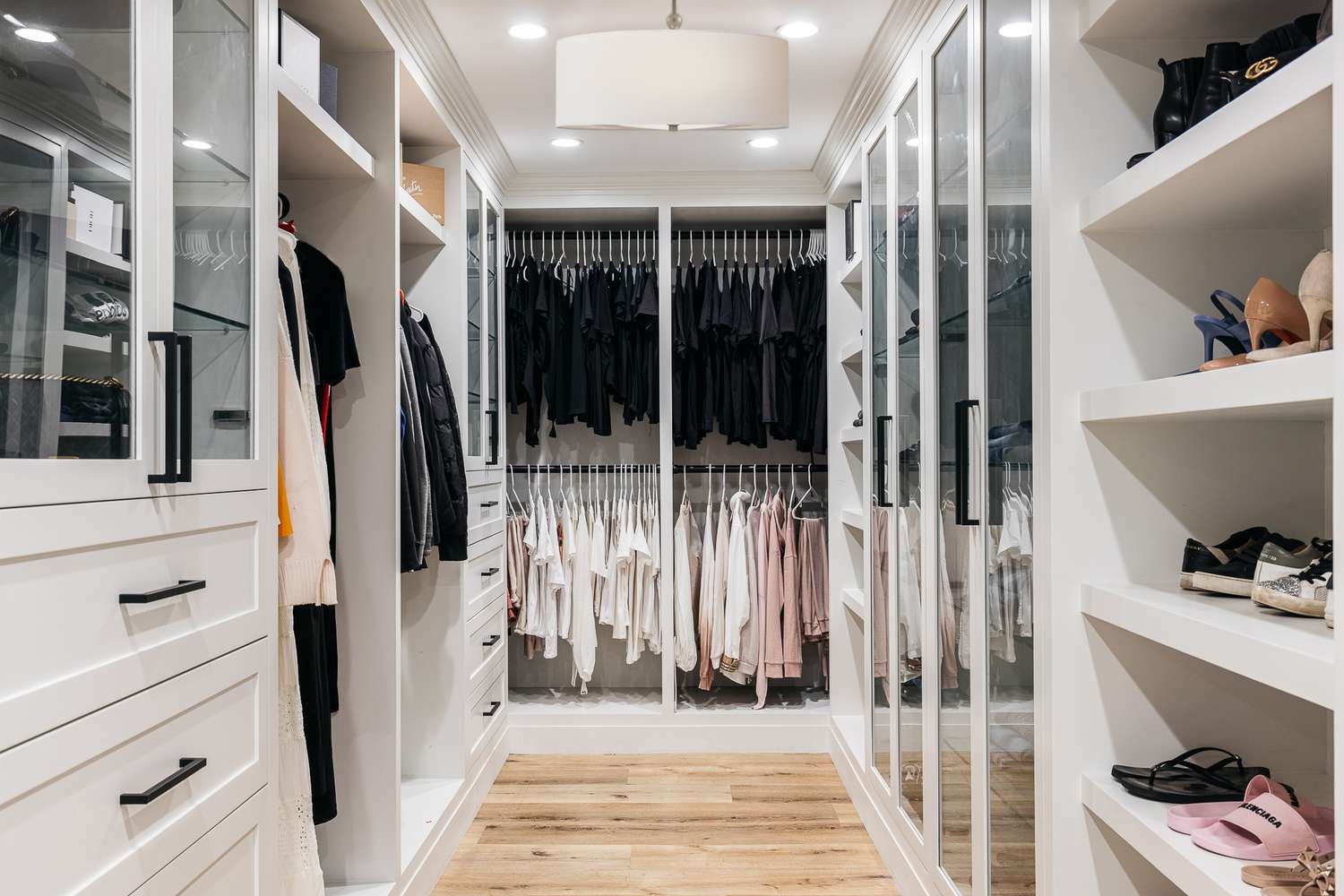 Closet com iluminação embutida e suspensa e armários e prateleiras brancos