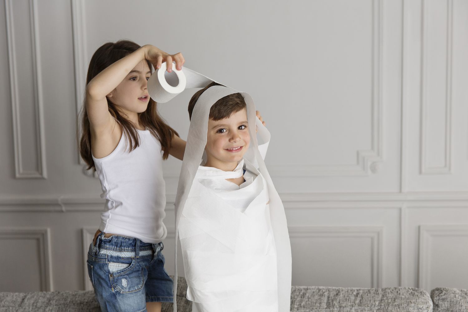 Mädchen wickelt Toilettenpapier um jüngeres Kind