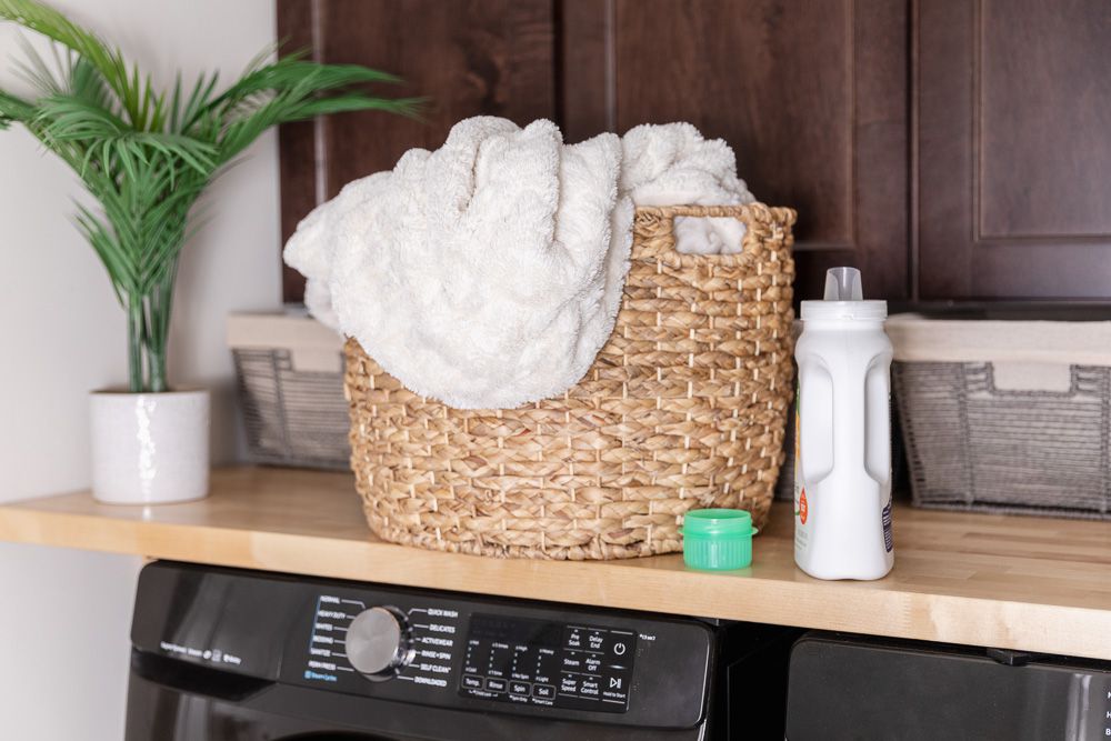 Wäschekorb mit Handtüchern neben dem Waschmittel in Großaufnahme
