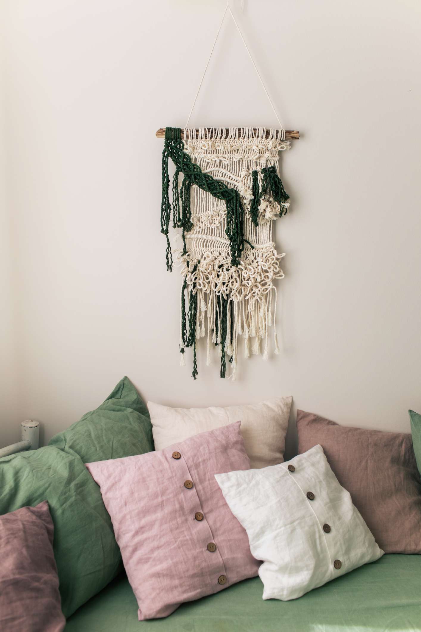 A bedroom with blush pink and macrame accents