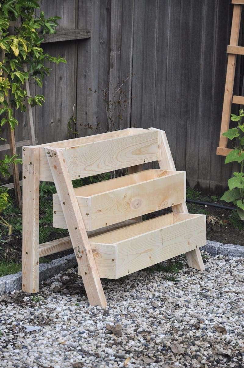 Ein gestufter Holzpflanzkasten auf Kies.