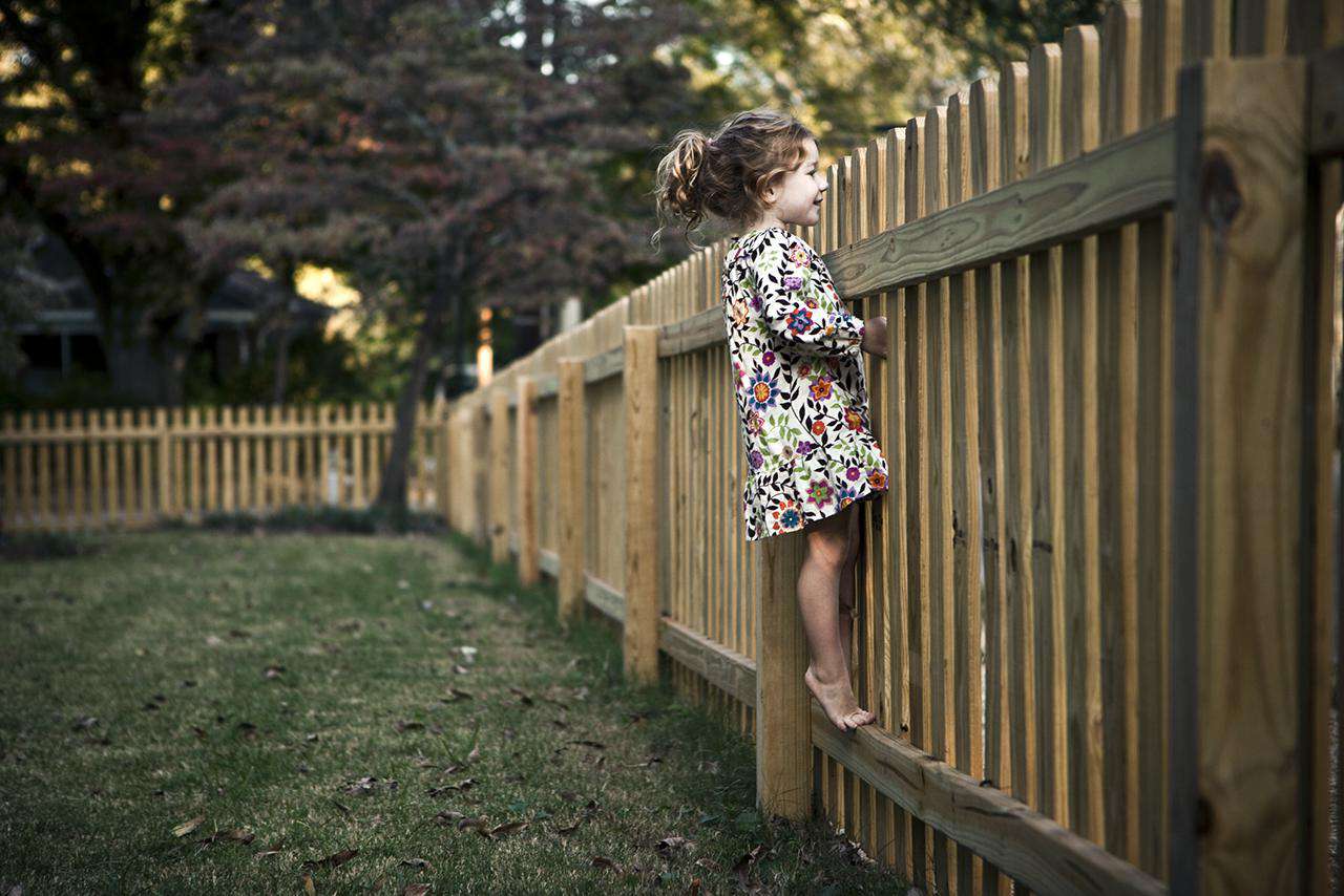 Mädchen (4 J.) späht über den Zaun
