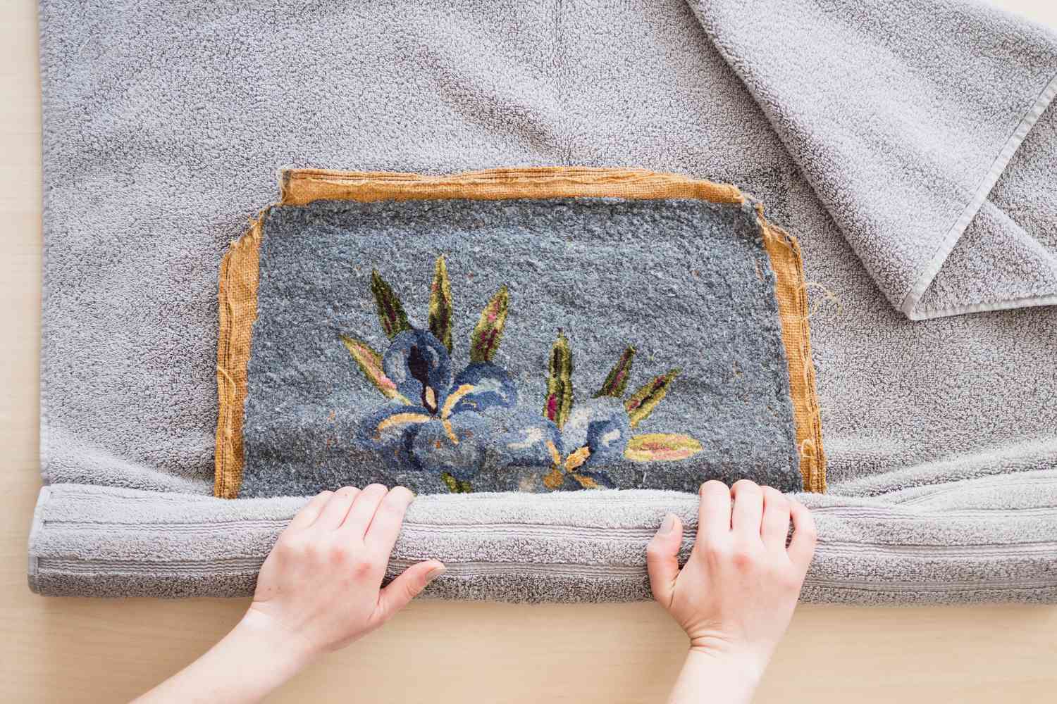 Peça de arte em ponto de agulha enrolada em uma toalha cinza para secar