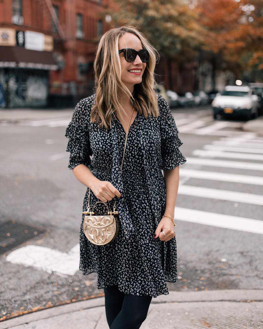 Mujer vestida de negro con gafas de sol de pie en la esquina de la calle