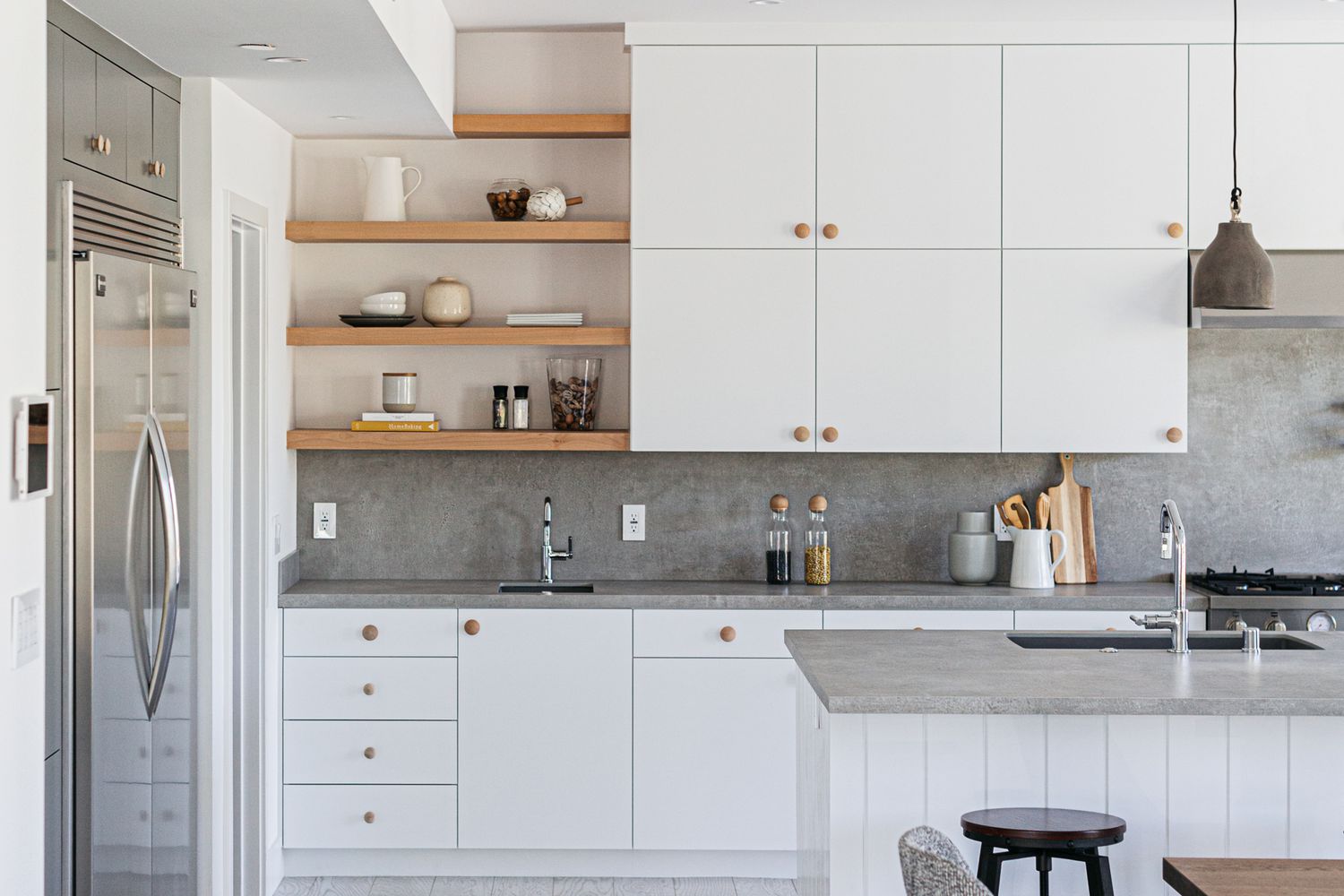 Weiße Küchenschränke mit grauen Arbeitsplatten und Holzregalen