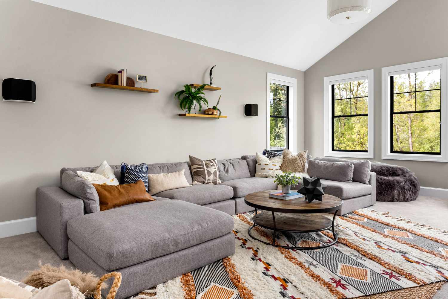 Bel intérieur de salle de séjour avec tapis coloré, grand canapé, et lumière naturelle abondante