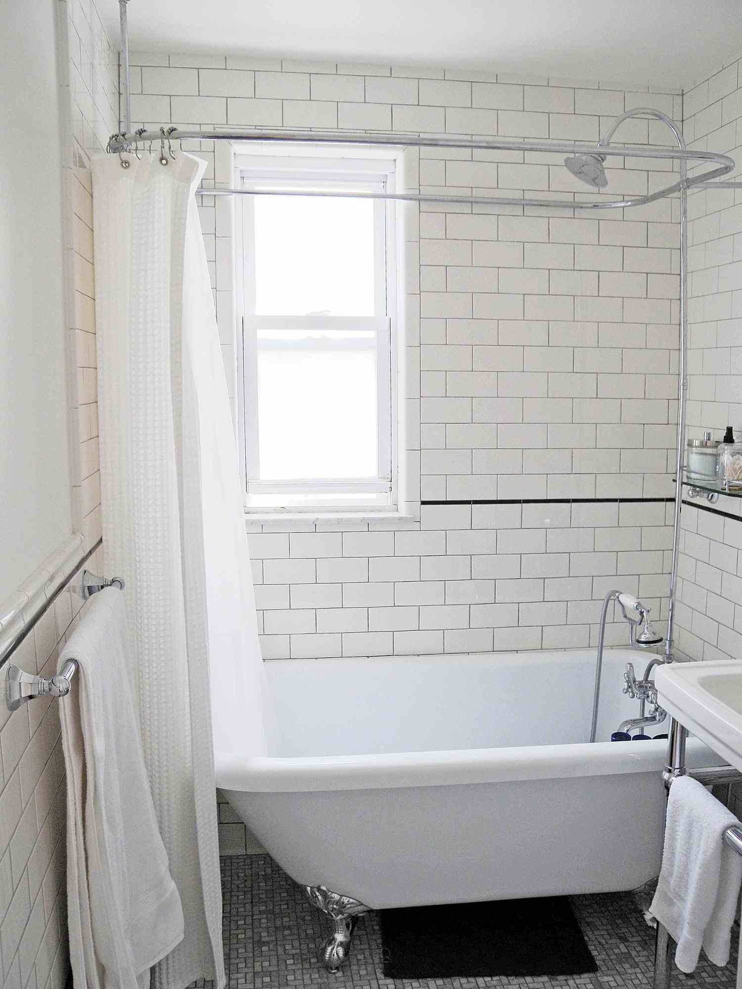Azulejos brancos de metrô e banheira com pés em forma de garra no banheiro reformado