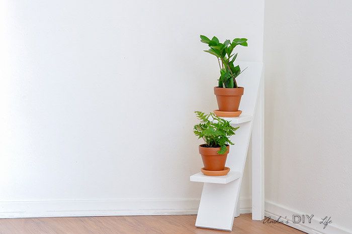 Suporte para plantas em camadas brancas com vasos de terracota.