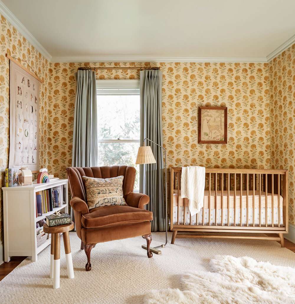quarto de bebê com papel de parede floral amarelo, poltrona almofadada, tapete branco fofo no chão