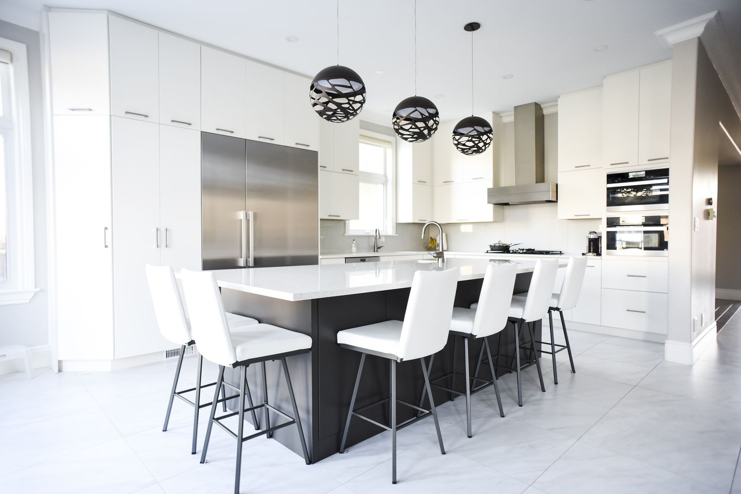 Moderna cocina blanca con gran isla y electrodomésticos de acero inoxidable.
