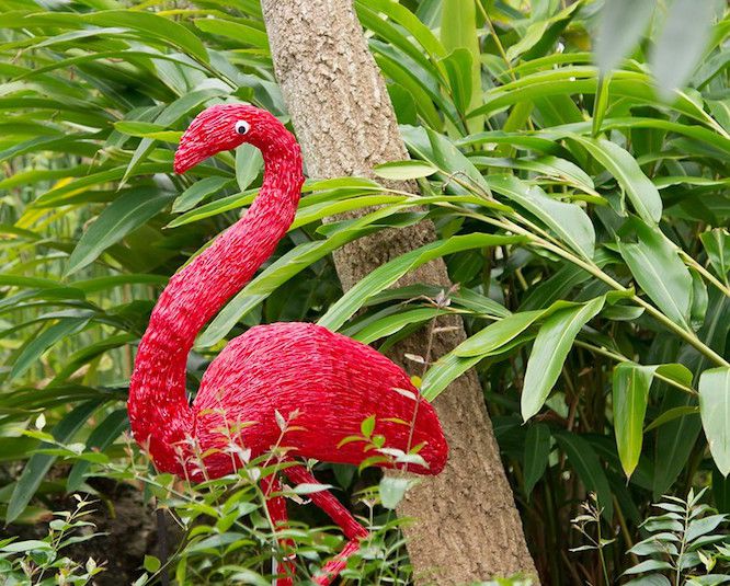 Red flamingo sculpture amid tropical garden