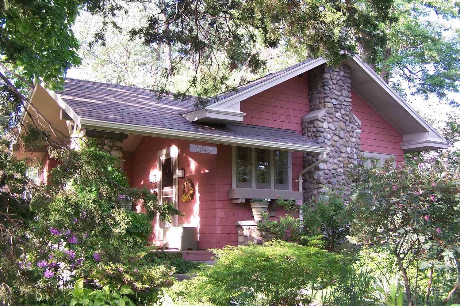 A Large Stone Chimney Is the Dominant Feature on This Rose-Colored Bungalow