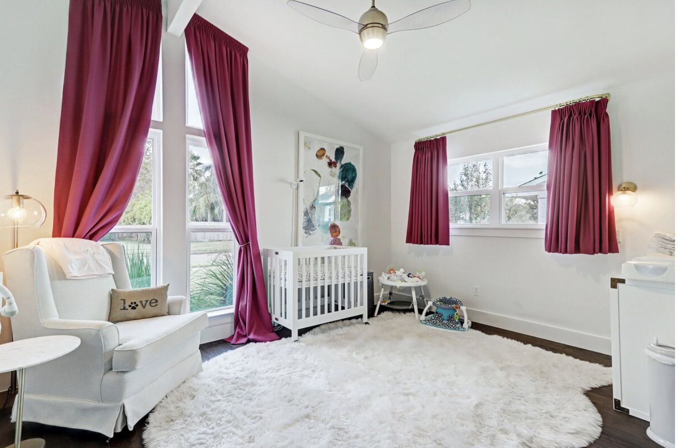 quarto de bebê com cortinas longas e curtas cor-de-rosa em um esquema de cores branco
