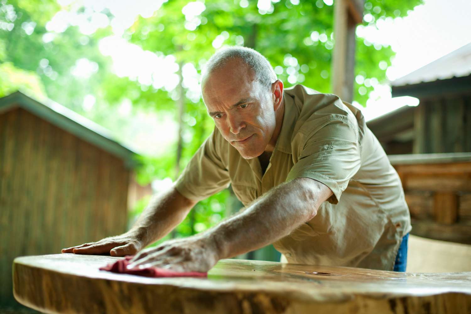 Mann reinigt Holz-Gartentisch