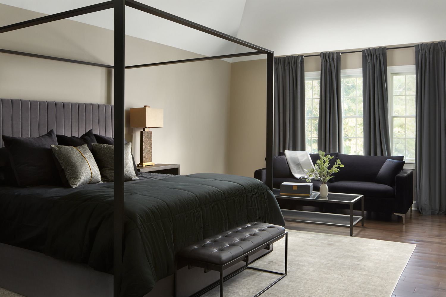 neutrales Schlafzimmer mit schwarzem Bettzeug und Rahmen, grauem Kopfteil und Vorhängen