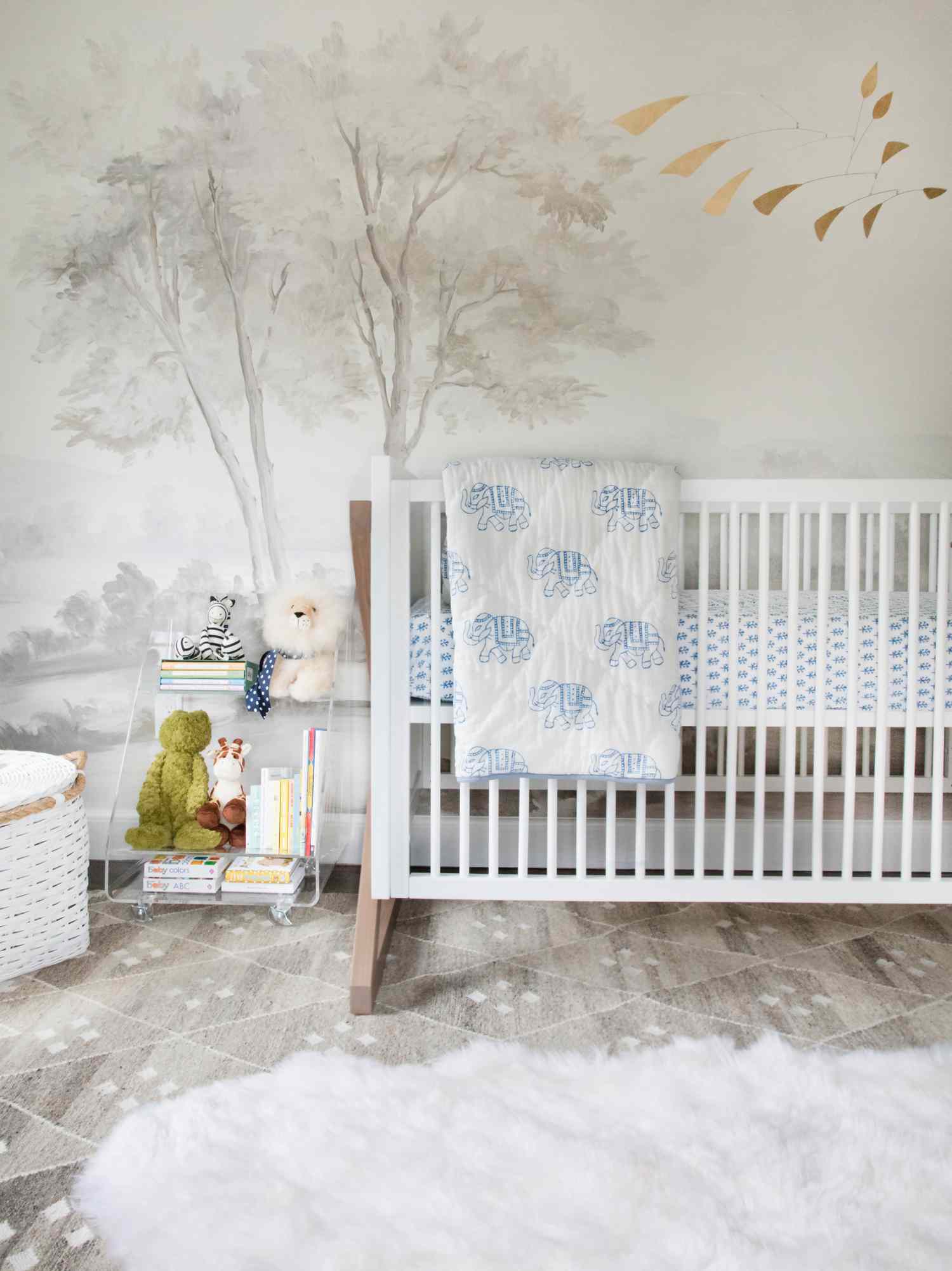 eine graue Wandtapete mit Baummotiven gibt den Ton für dieses zarte weiße Kinderzimmer an
