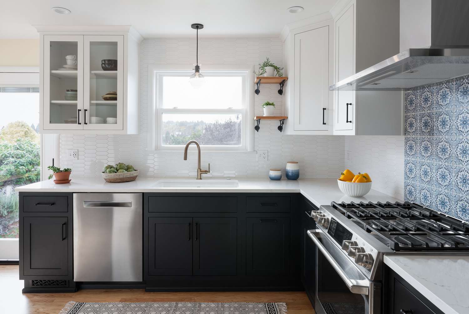 Uma cozinha com armários inferiores pretos, superiores brancos e um backsplash de fogão azul