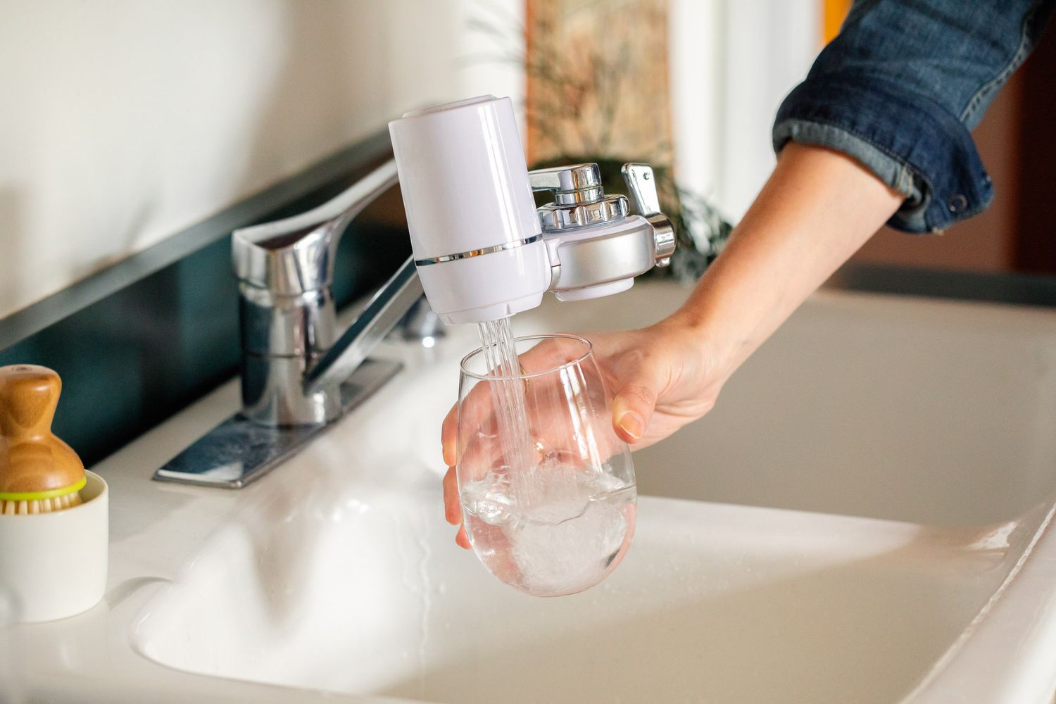 Glas wird mit Wasser aus einem Wasserhahn mit Wasserfiltersystem gefüllt
