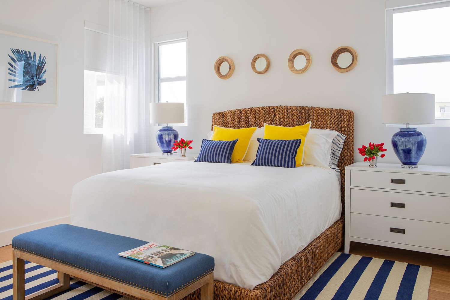 quarto primário com paredes e cama brancas, com toques de amarelo, azul e vermelho