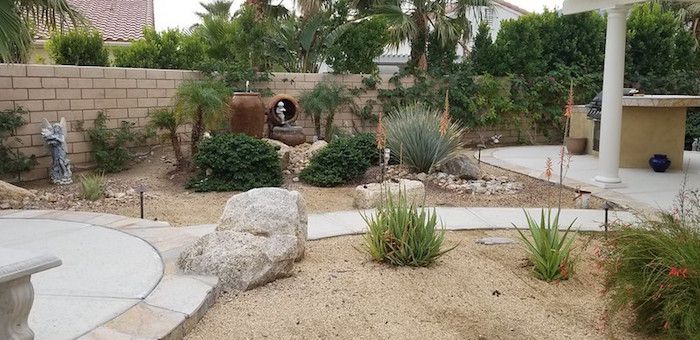 Jardin avec sable, allées en ciment et sculptures