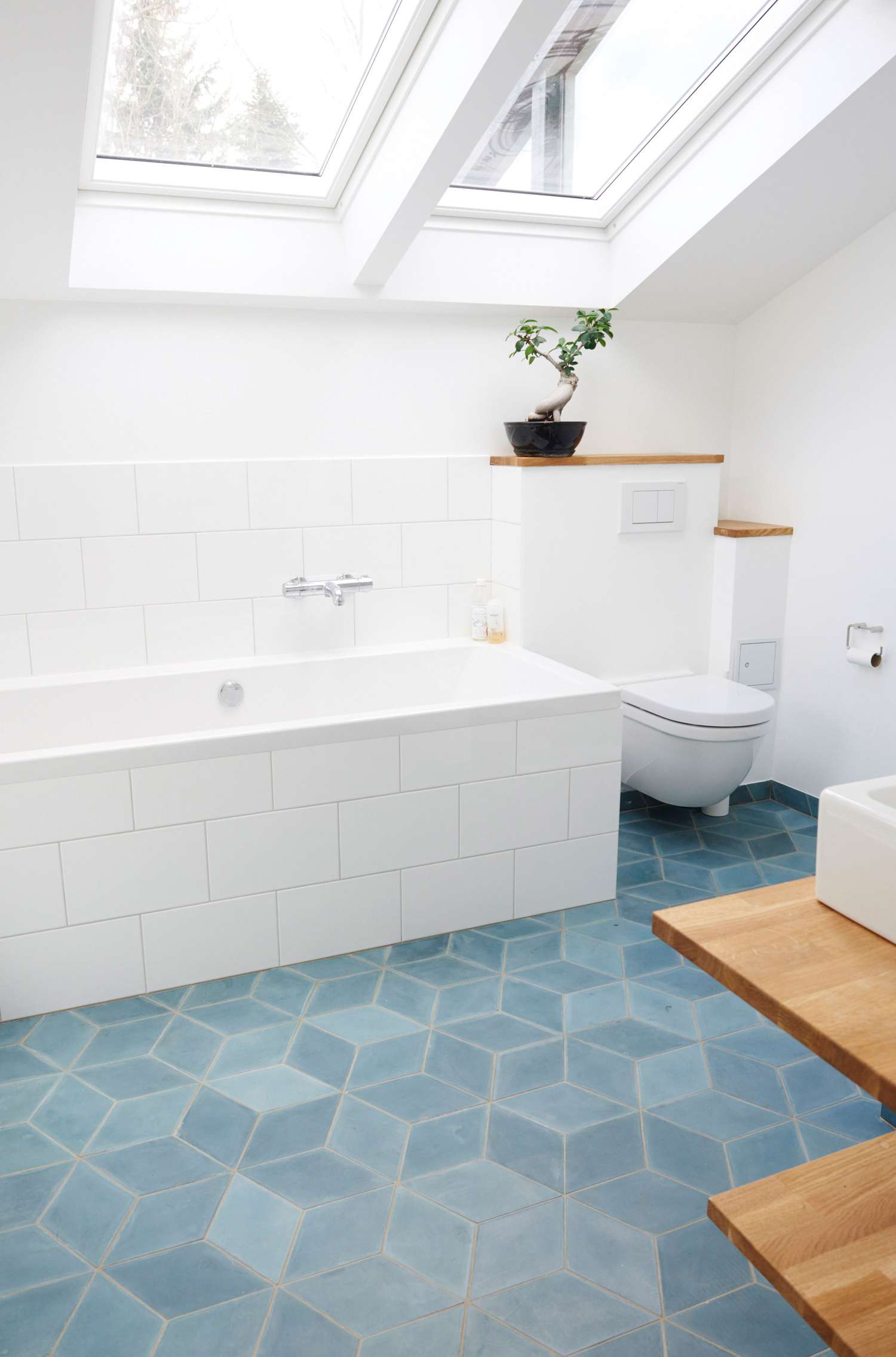 Banheiro branco com azulejos azuis e detalhes em madeira