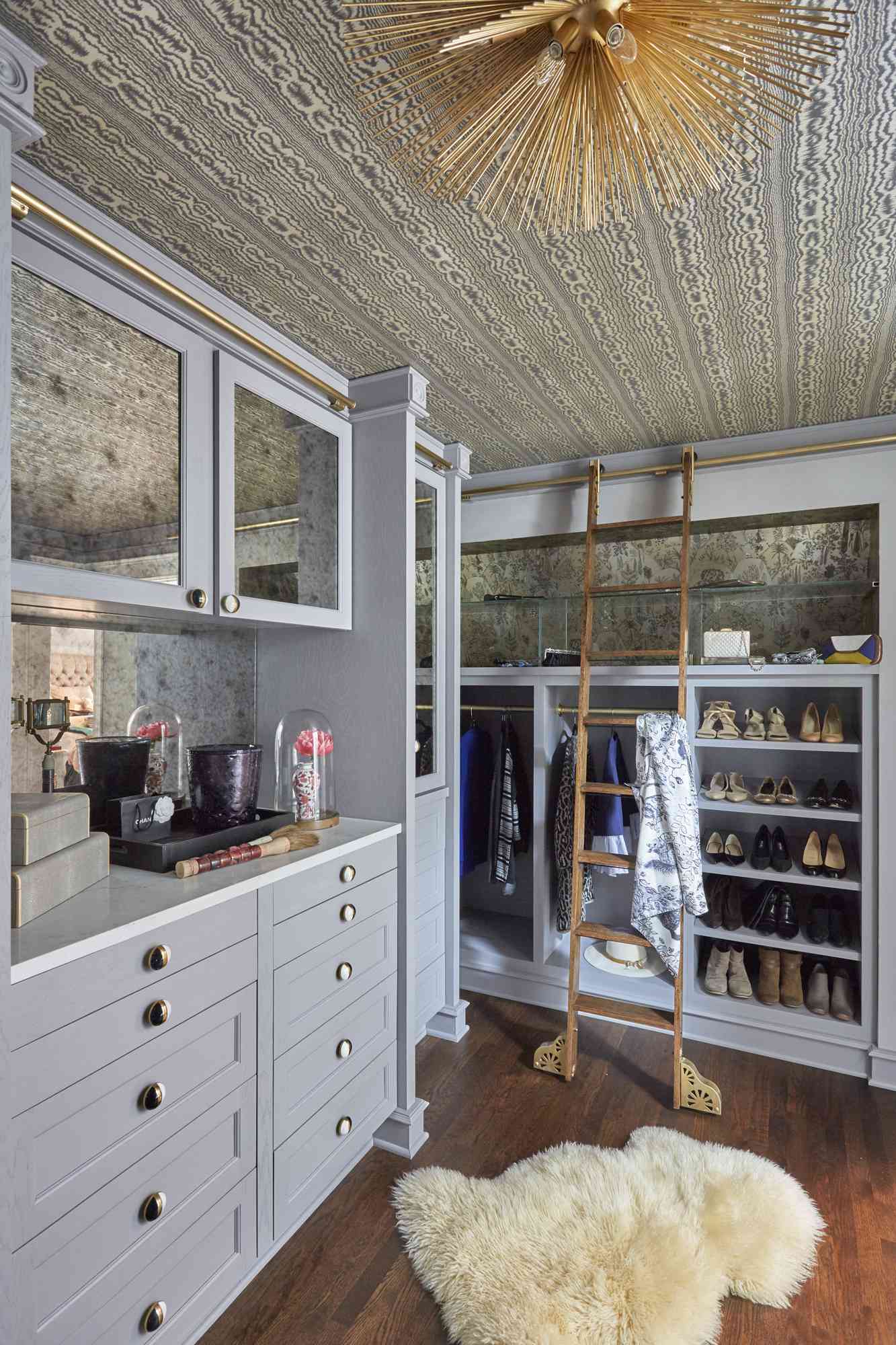 gris walk-in closet with gold light fixture