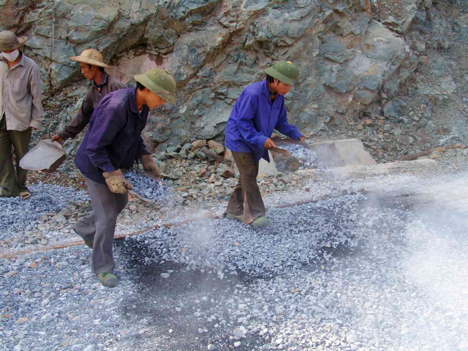 Trabalhadores construindo uma estrada de piche e cavaco.