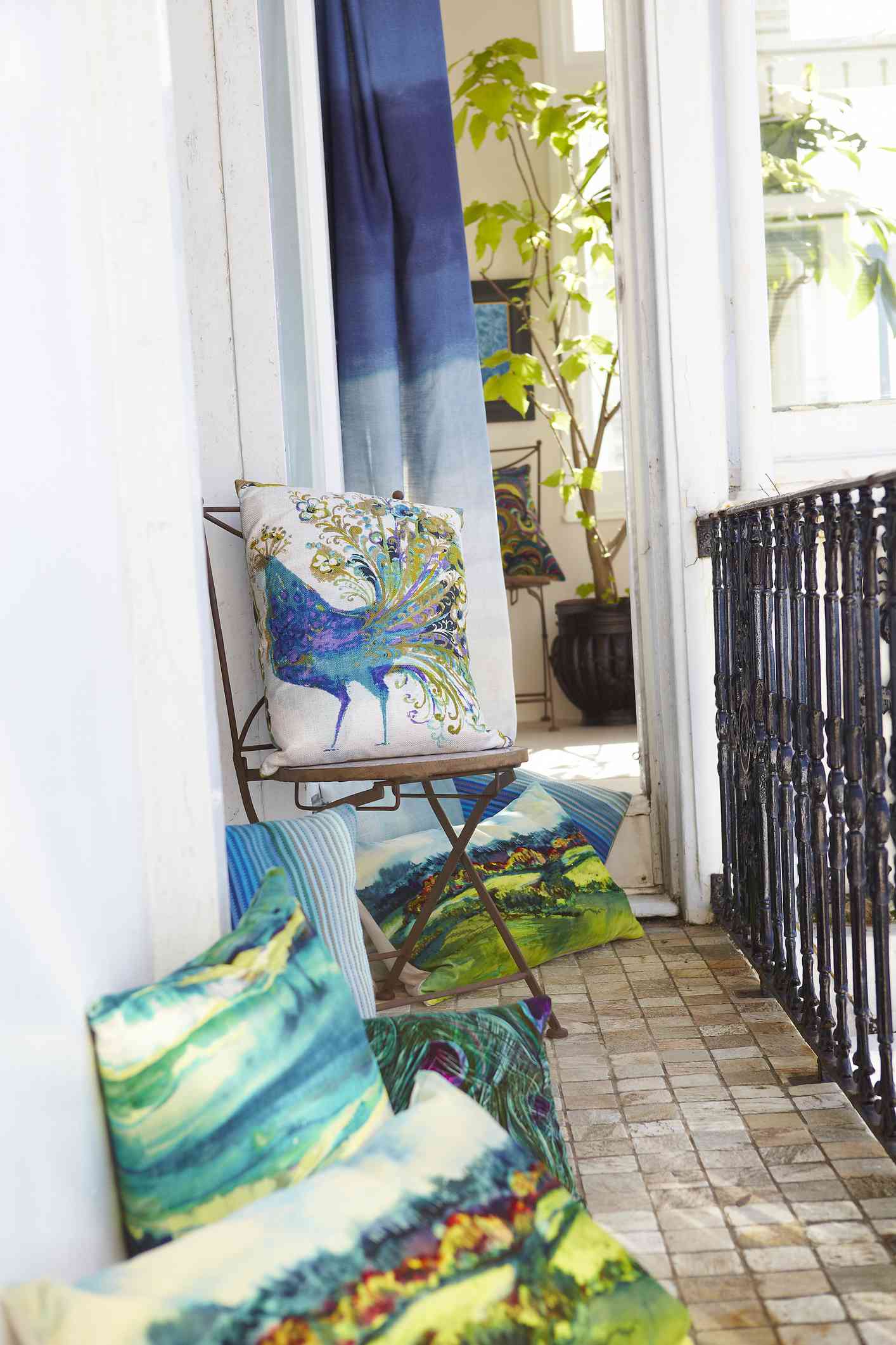 Vista del balcón con coloridos cojines de pavo real sobre una silla