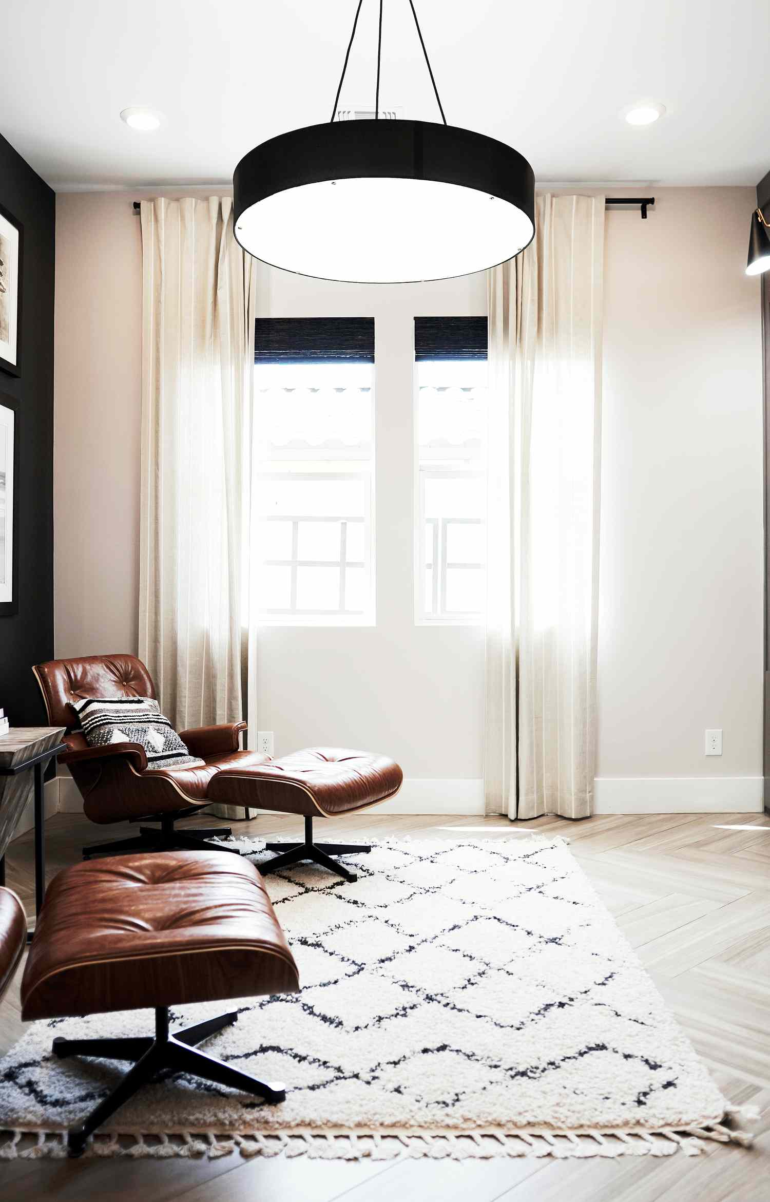 sala de estar preta, branca e marrom com uma cadeira, pufe e tapete marroquino