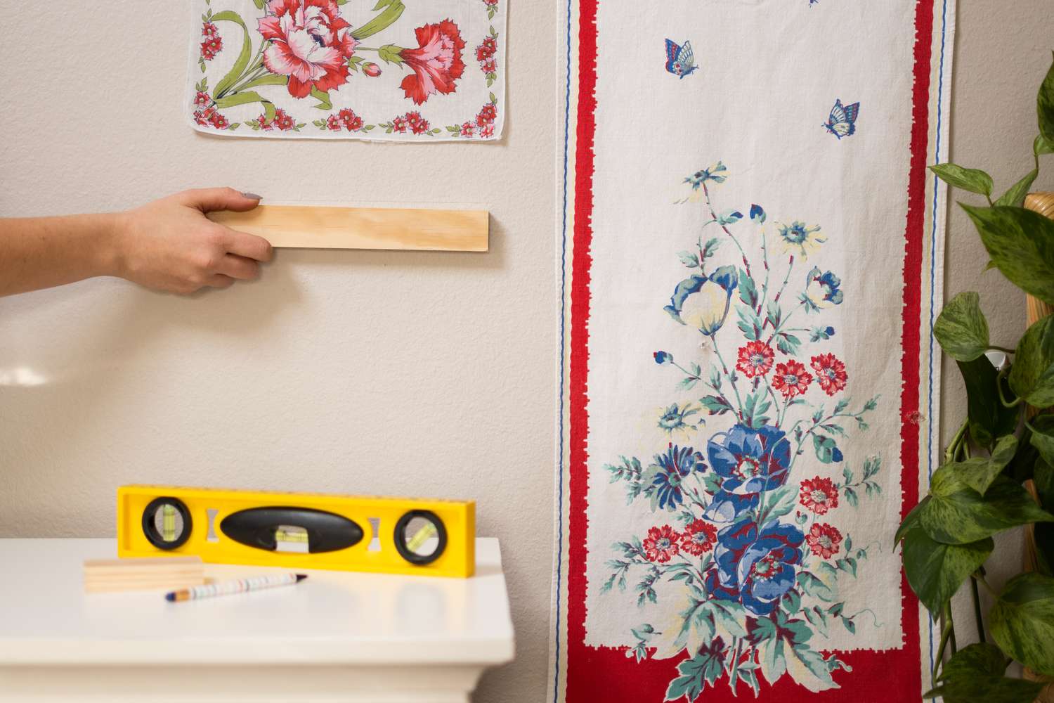 Holzbrett mit Bleistiftmarkierungen an der Wand zum Aufhängen von Textilien