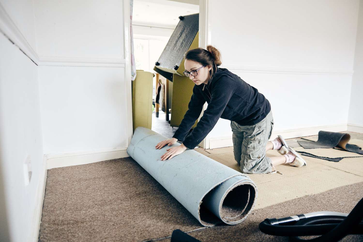 Señora quitando la moqueta de una habitación