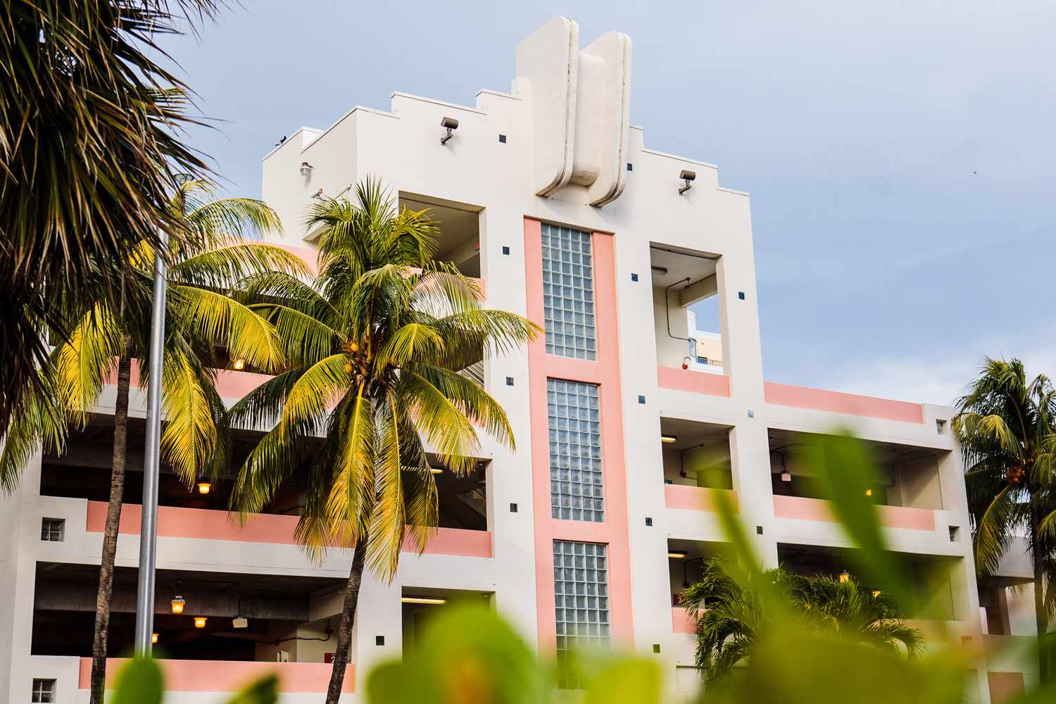 Weißes und rosafarbenes Parkhaus im Art-déco-Stil mit Palmen davor