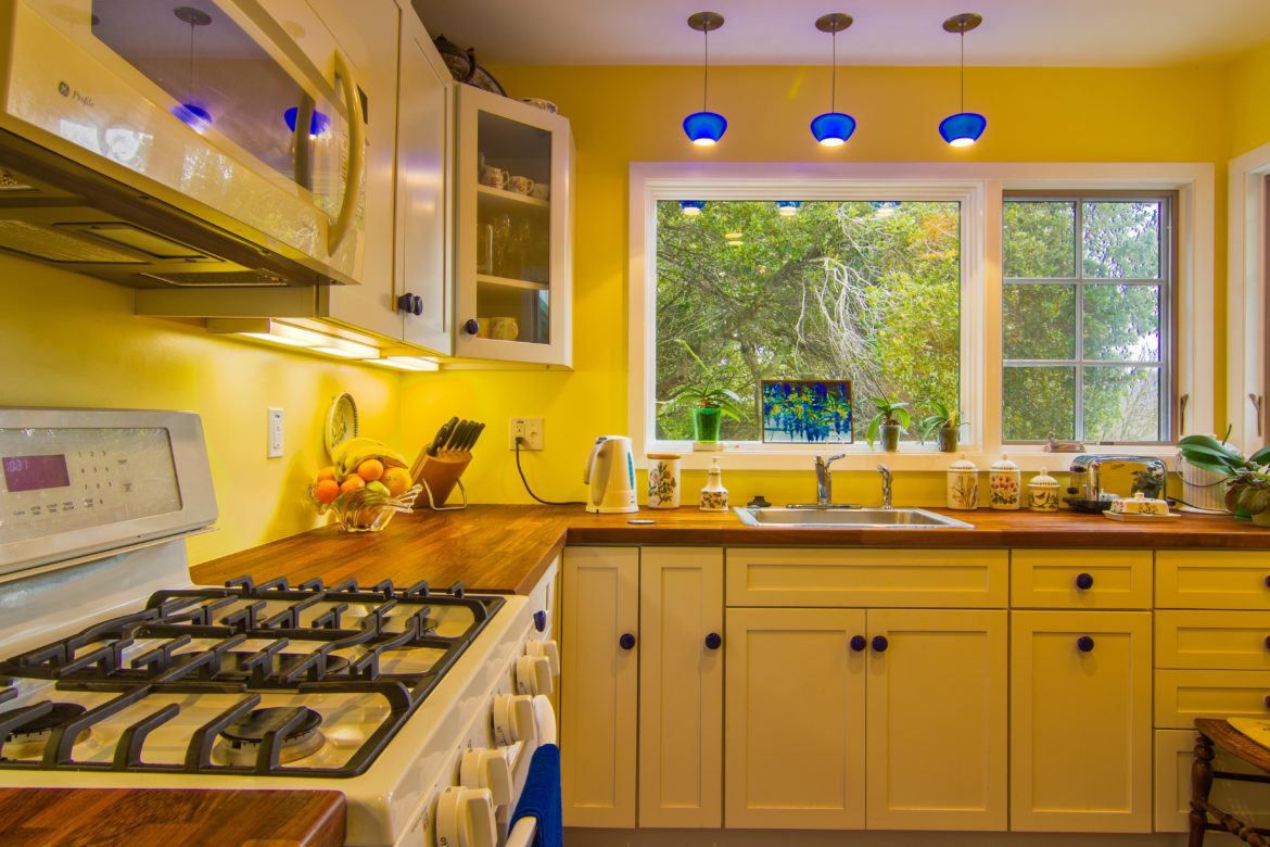 Cozinha de chalé com paredes e armários amarelos