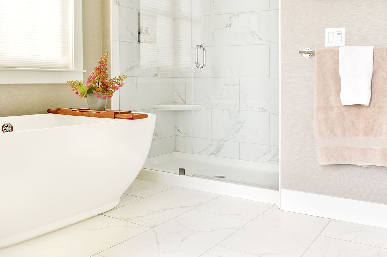 Salle de bain avec tan and light gray marble tile around white tub closeup