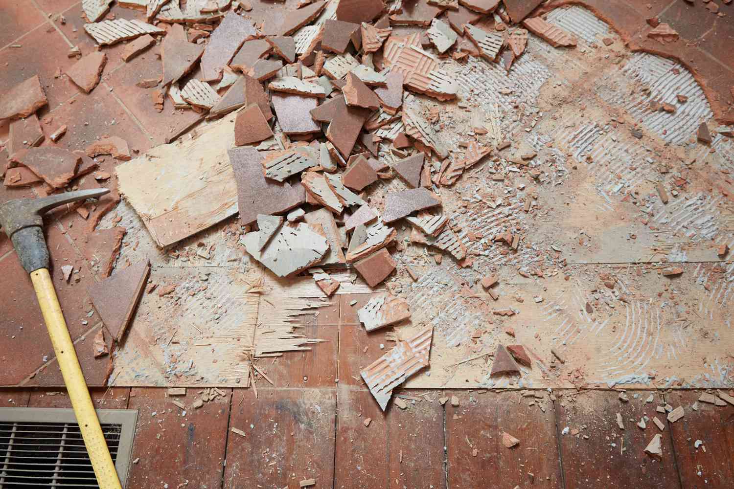 Bord du sol avec des carreaux de céramique bruns cassés en petits morceaux avec un ciseau à maçonnerie